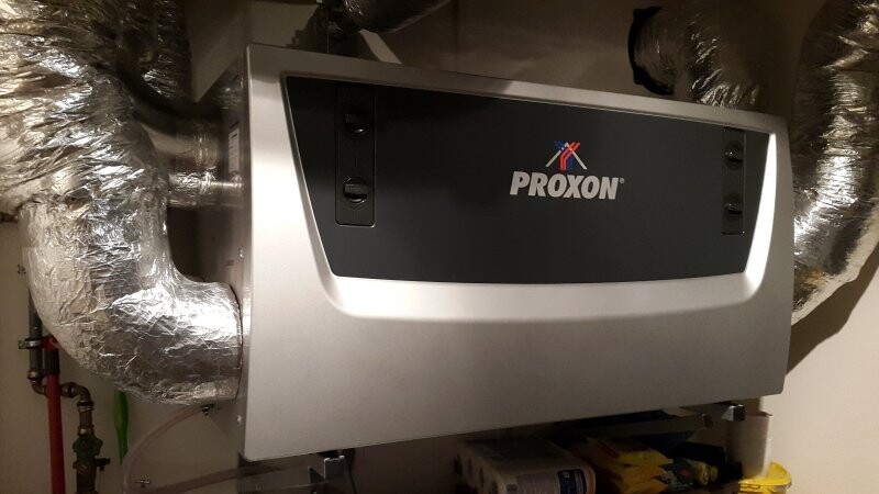 PROXON Heizgerät/Kessel mit silberner Abdeckung, umgeben von isolierten Luftleitungen.