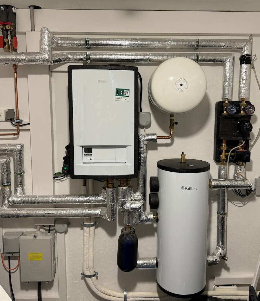 Heizungsanlage im Technikraum mit Vaillant Boiler, Warmwasserspeicher und isolierten Rohren