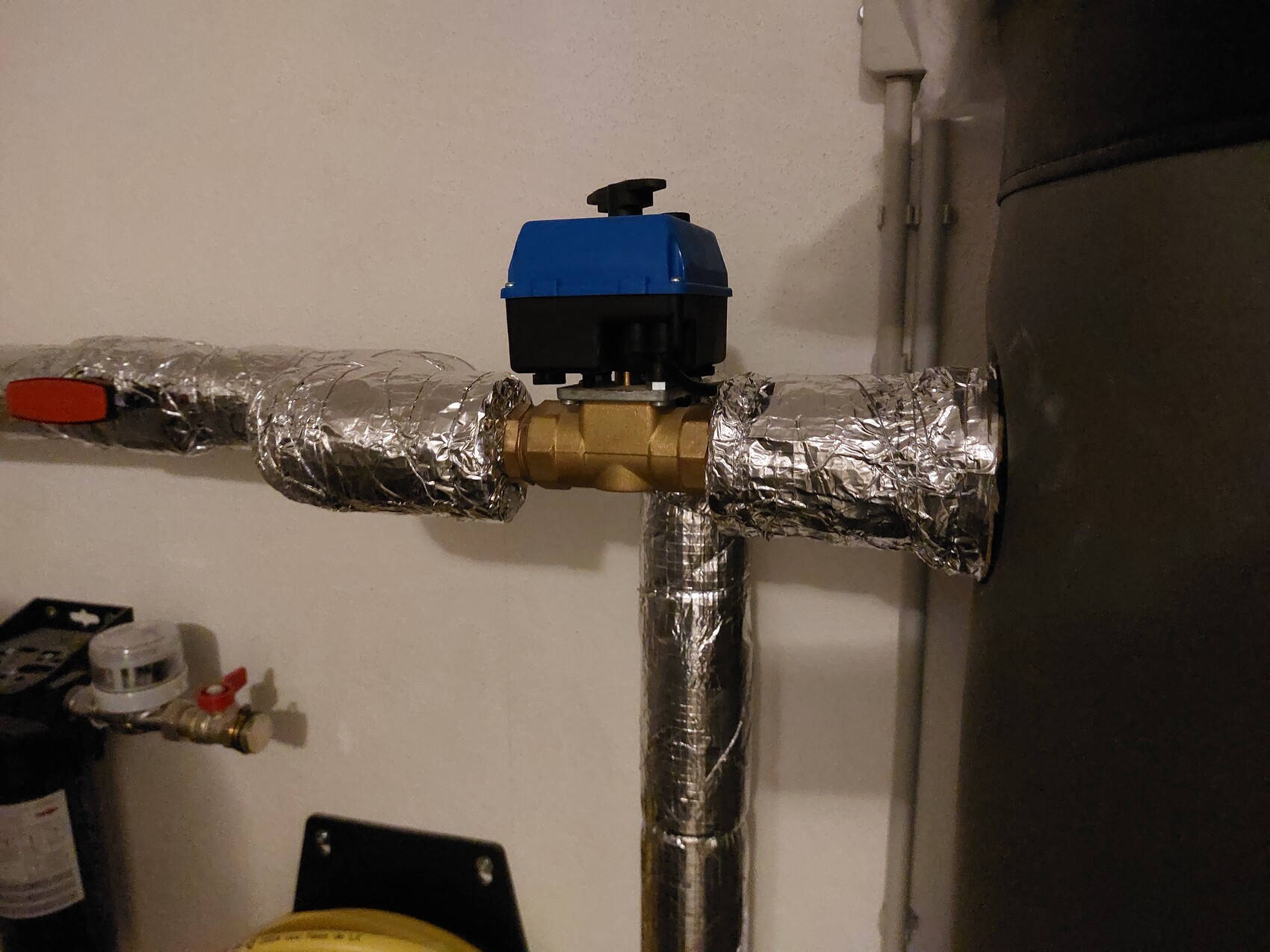 Isolierte Heizungsrohre mit blauem Absperrventil im Kellergeschoss