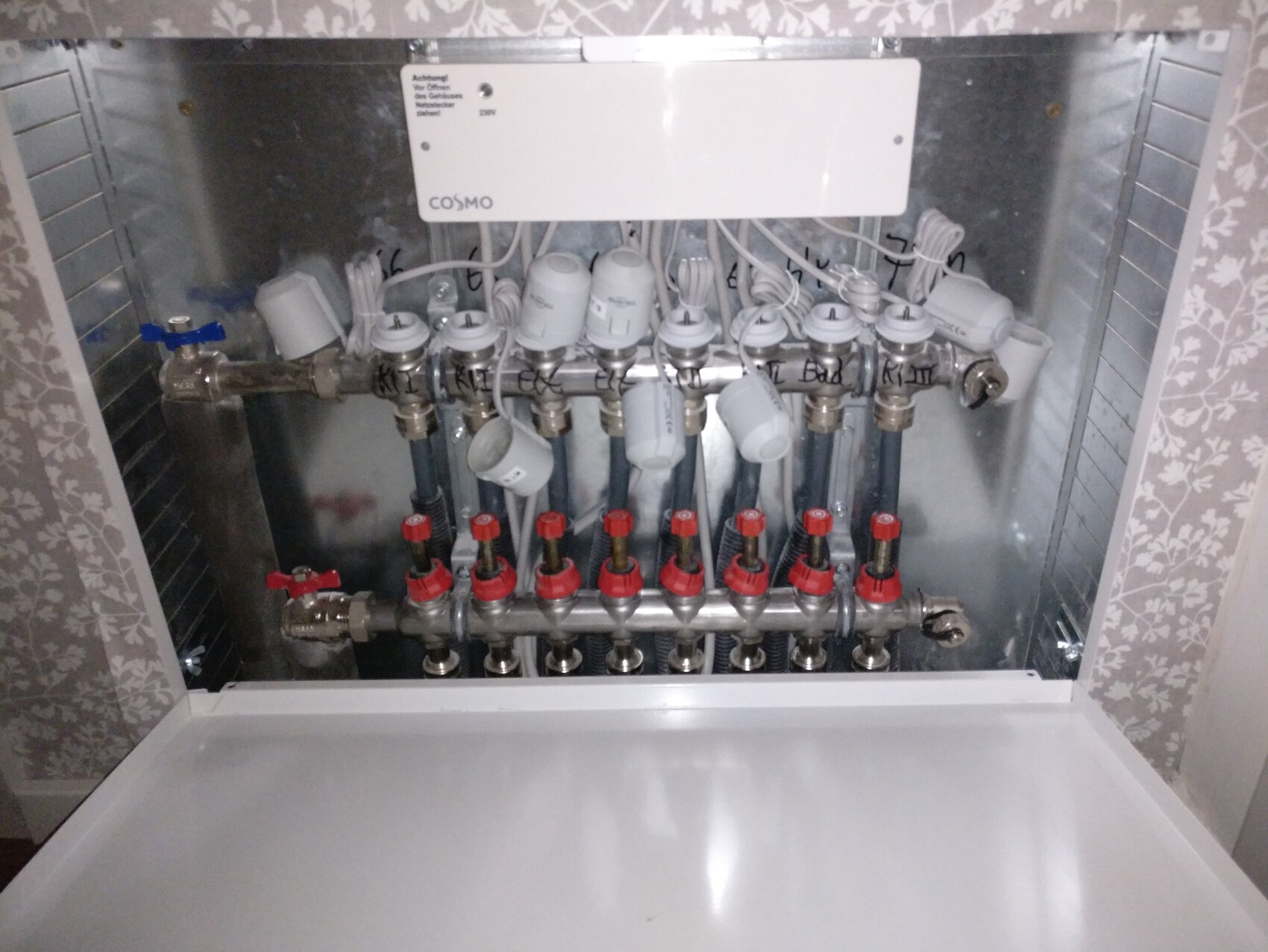 Verteilungsblock eines Heizsystems mit roten Absperrventilen im Schrank