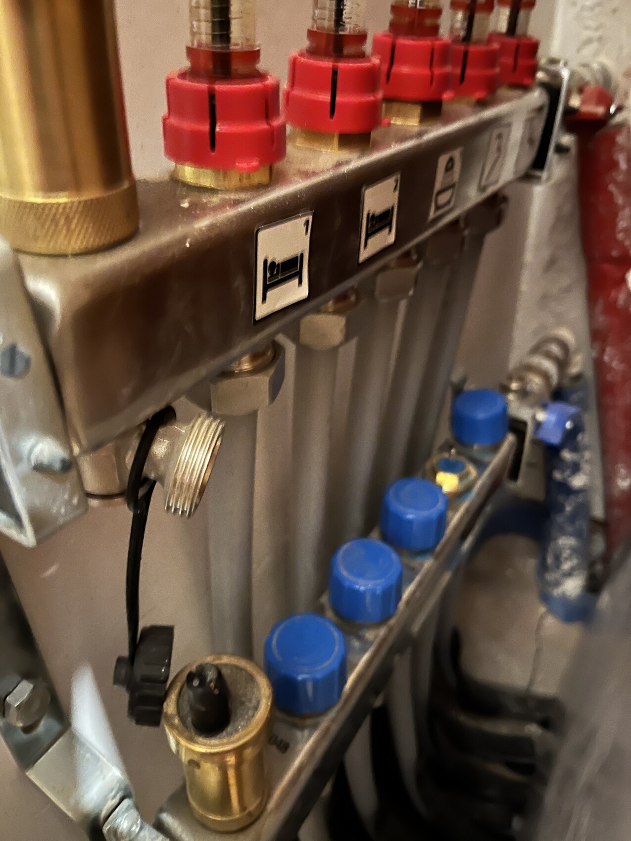 Nahaufnahme eines Ventilpanels mit roten Knöpfen, Metallgehäuse und blauen Abdeckkappen