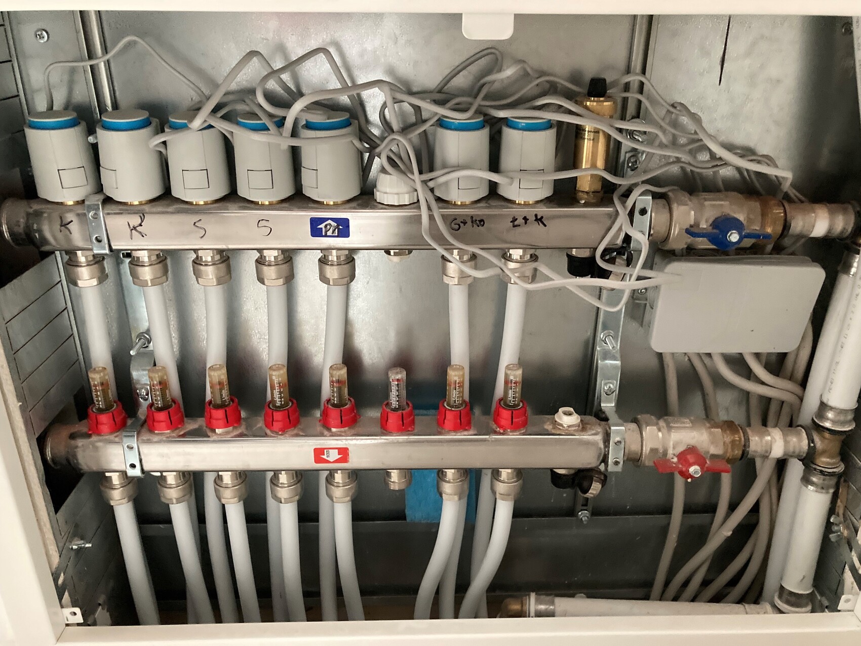 Mehrkanal-Verteiler mit Ventilen, Durchflussmessern und Kabelsalat in einem elektrischen Schrank.
