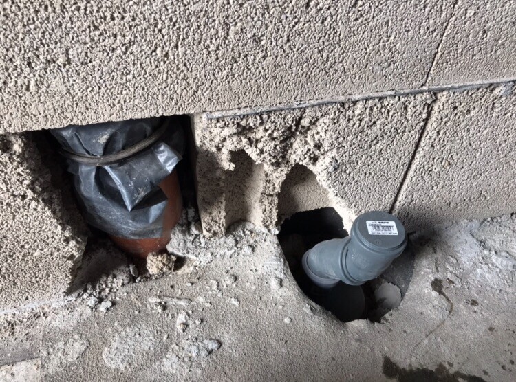Rohbauwand mit offenen Rohrleitungen und grobem Putz, Haustechnik im Bau
