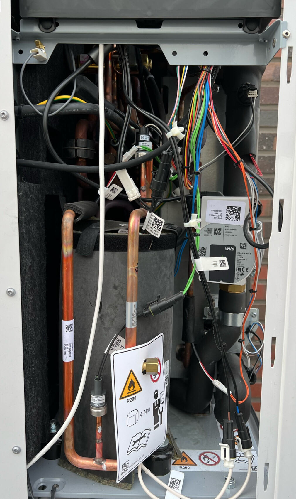 Innenansicht eines Klimageräts mit Kupferrohren, Kabelsalat und Wilo-Pumpe (R290)