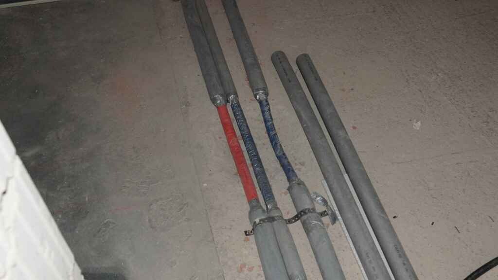 Mehrere Rohre liegen auf dem Baustellenboden, Installationsleitungen im Rohbau.