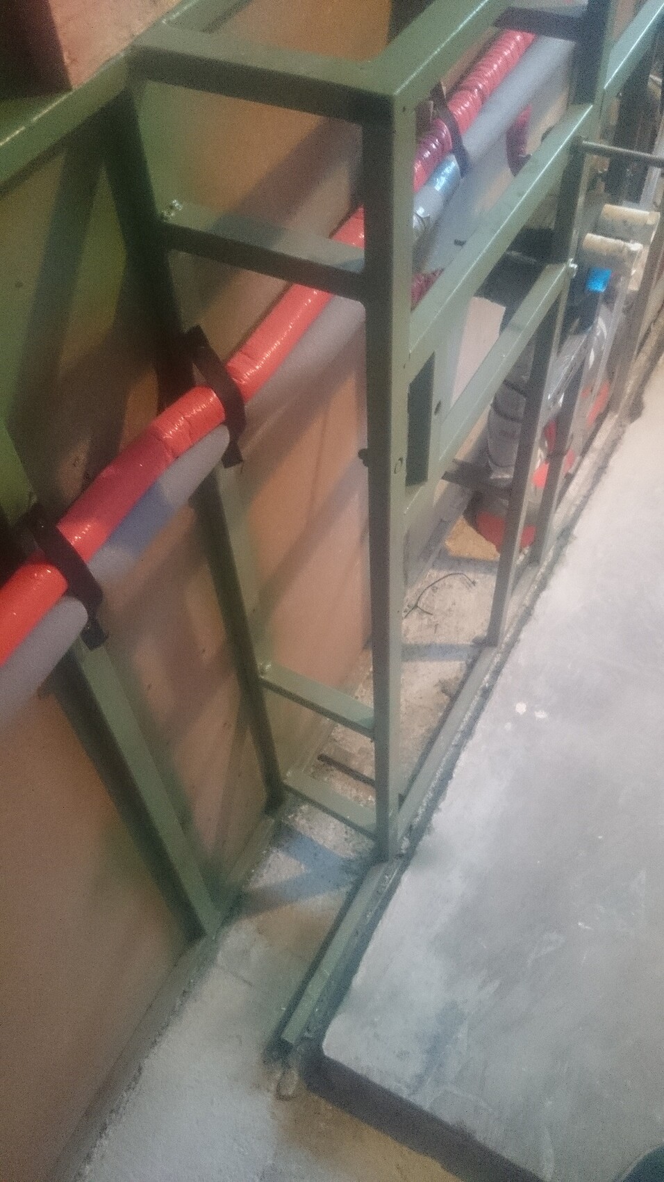 Grüne Metallrahmenkonstruktion mit Rohren und Kabeln an Wand in Bauwerkstatt