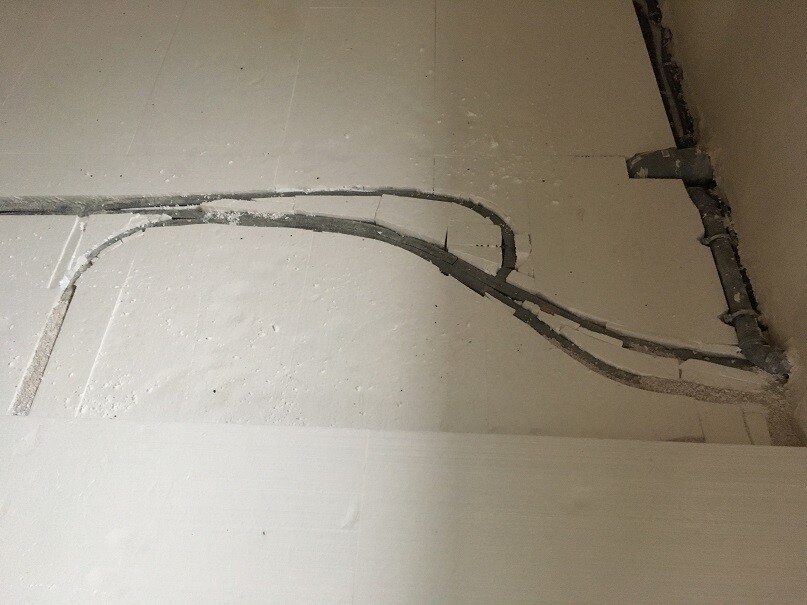 Rohbau-Boden mit sichtbaren Kabel- und Rohrleitungen auf Baustelle