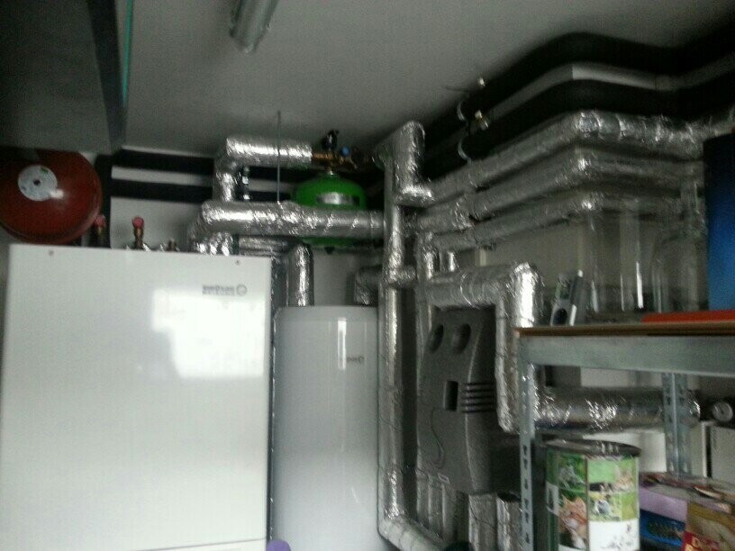 Technikraum mit Heizungsanlage, isolierten Rohren, Tank und Werkbank