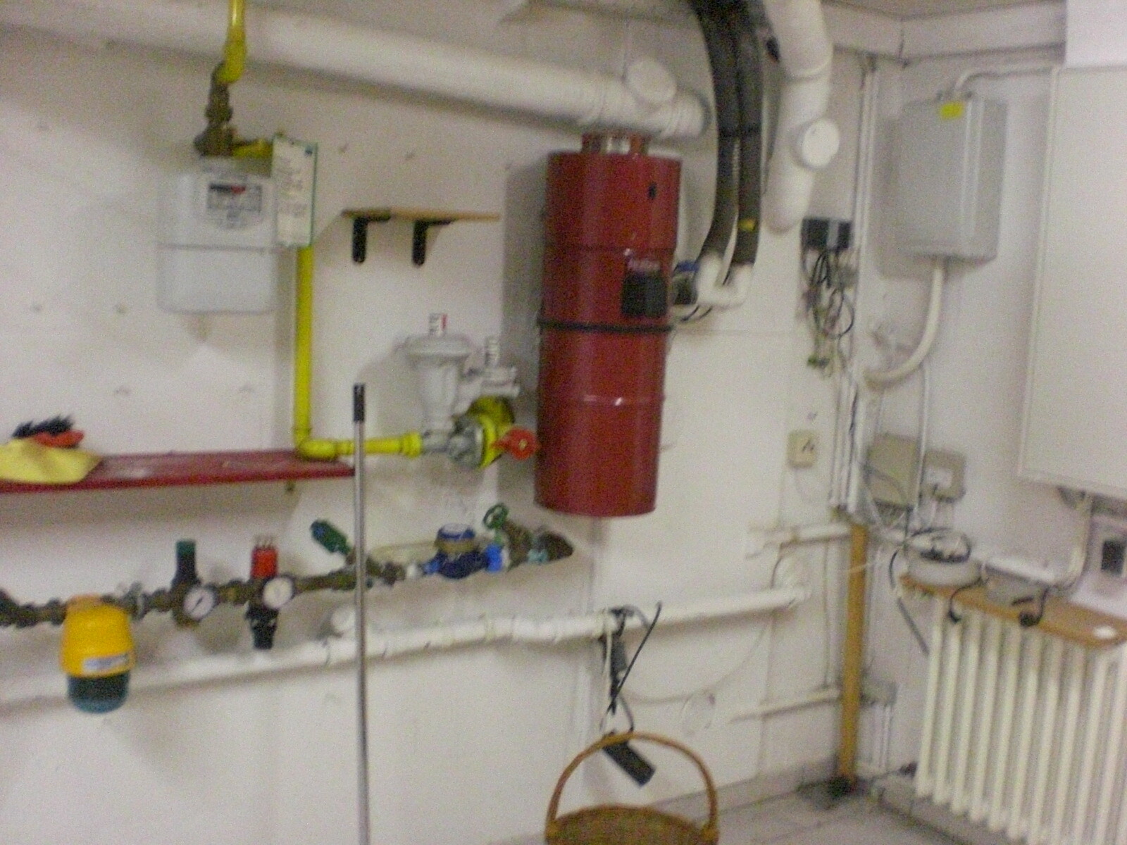 Kellerraum mit Heizungsanlage, Rohrleitungen, roter Heizkessel und Heizkörper.