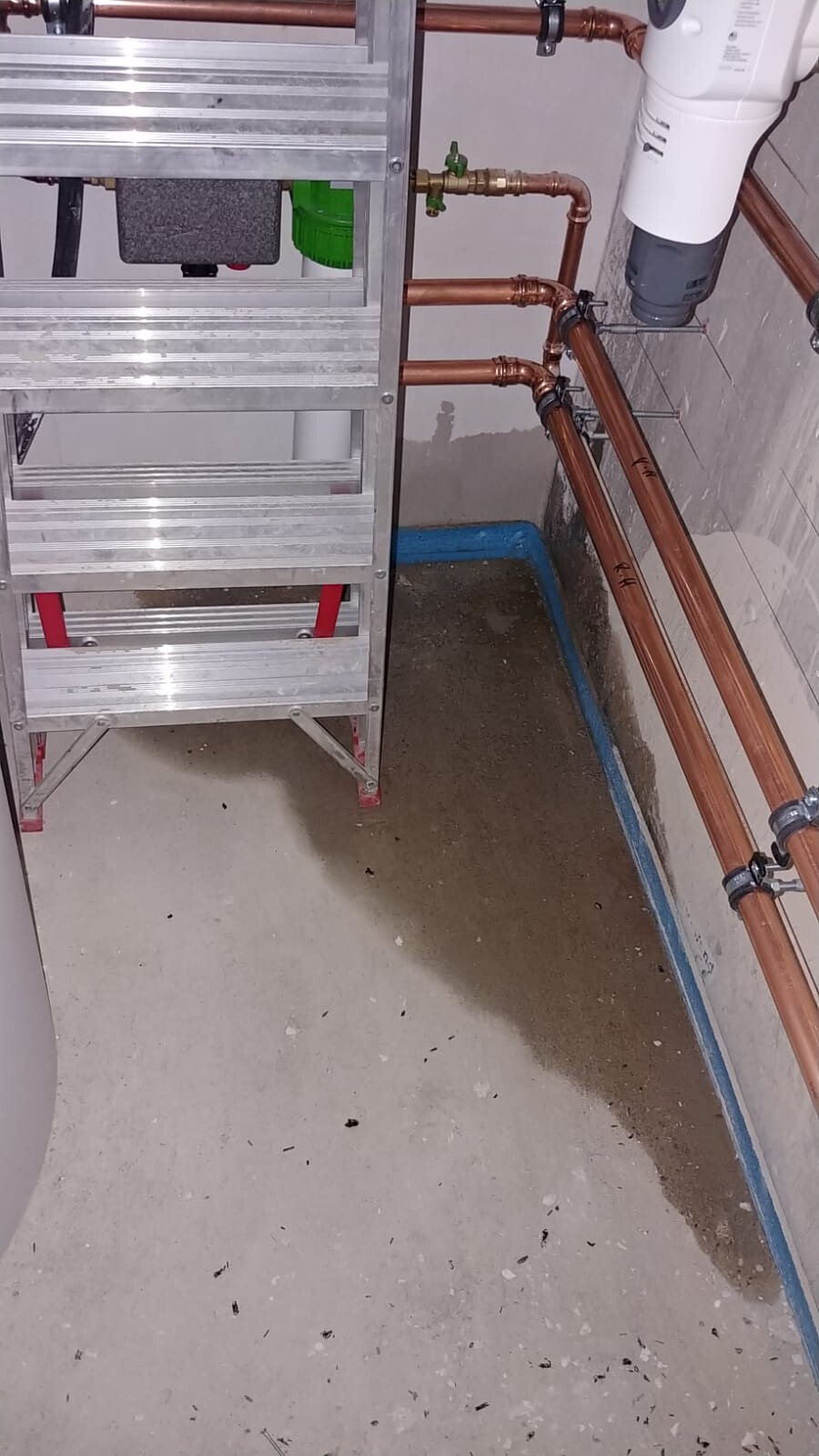 Kellerraum mit Kupferrohren, Heizungs- und Sanitärinstallation neben Metallleiter