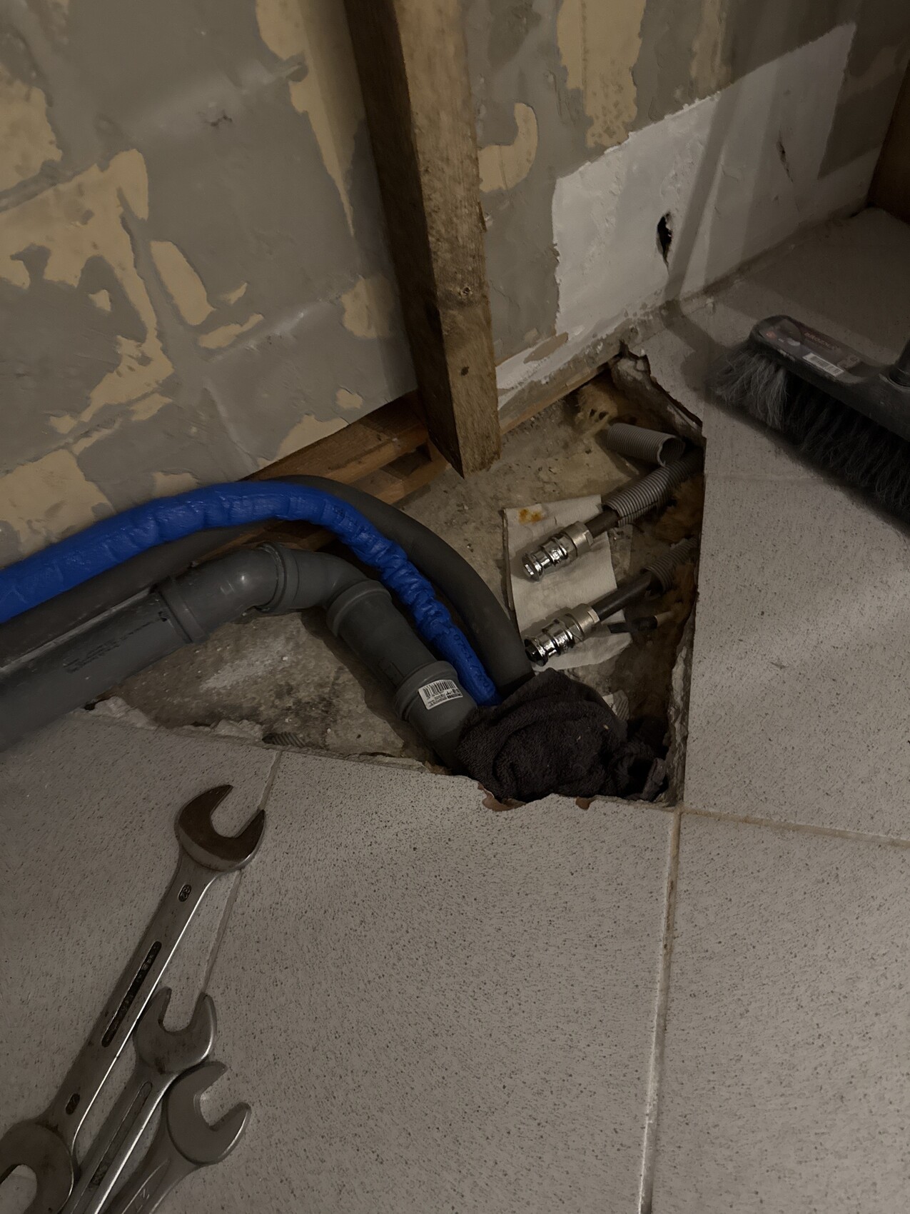 Unterbodenbereich mit offenliegenden Rohrleitungen, Schläuchen und Werkzeugen beim Bau