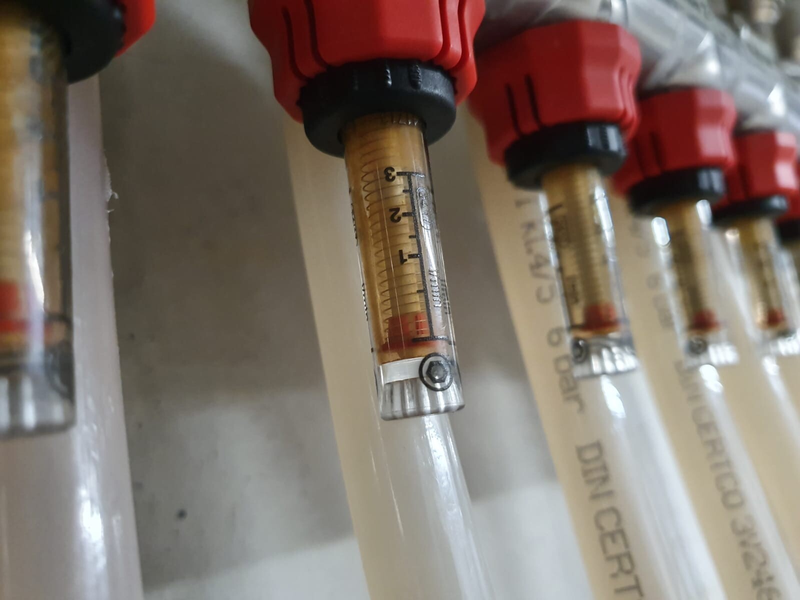 Nahaufnahme von Rohrleitungen mit Messskala und roten Anschlüssen in Haustechnik-Installation