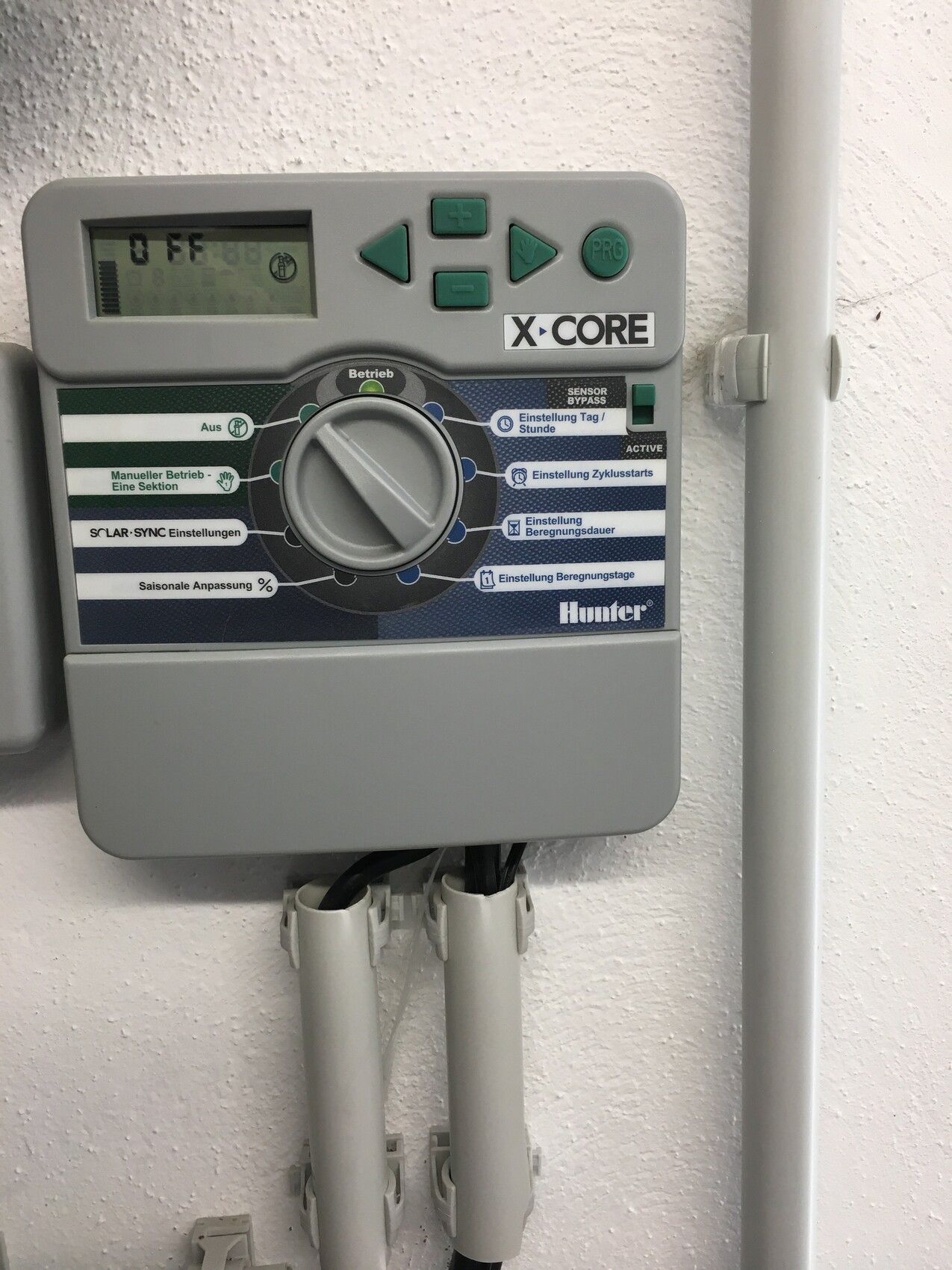Graues Bewässerungssteuergerät mit Drehknopf, X-CORE von Hunter, unten Rohre.