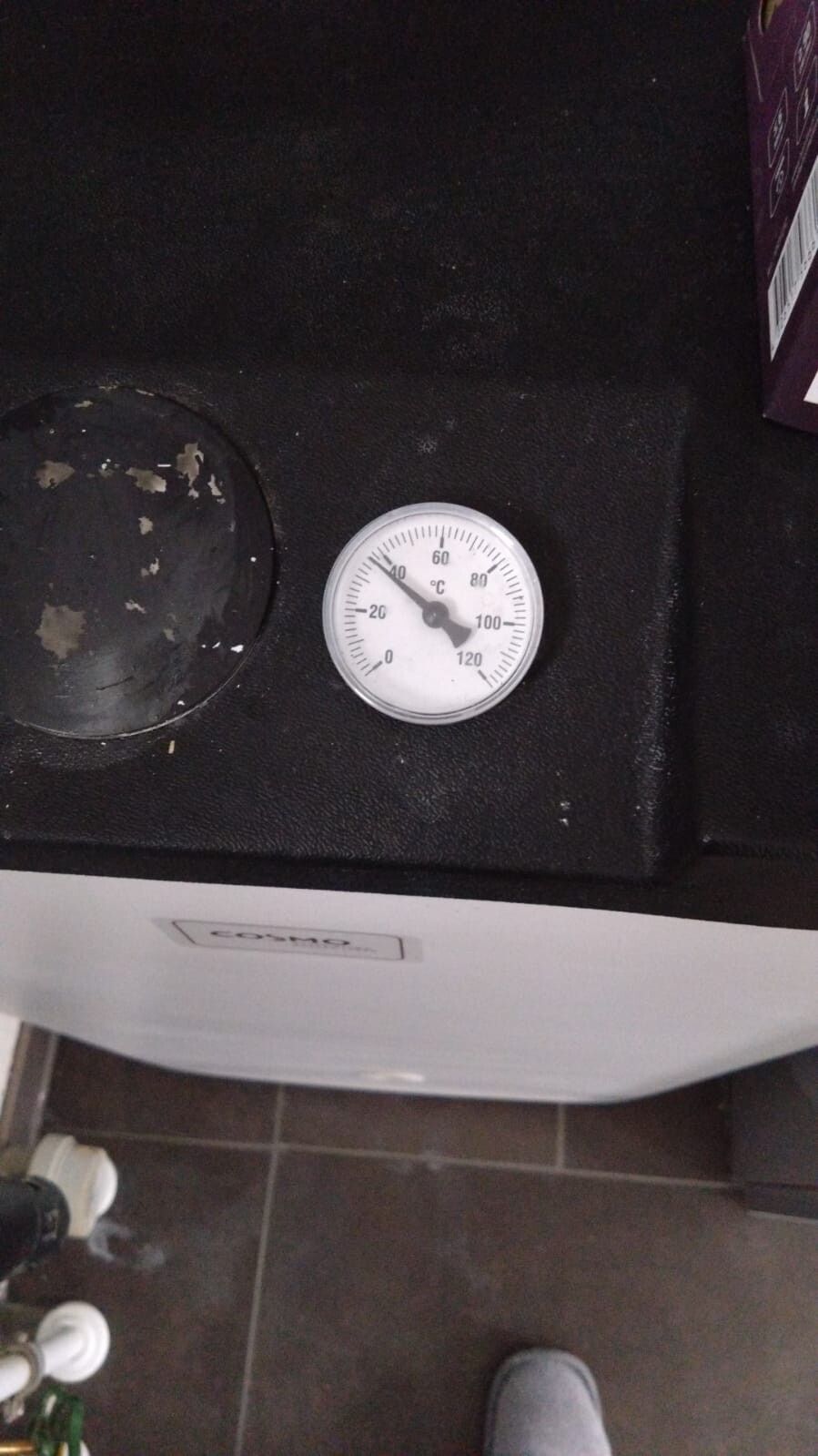 Thermometer mit 0–120 °C auf schwarzer Oberfläche, daneben runder Deckel.