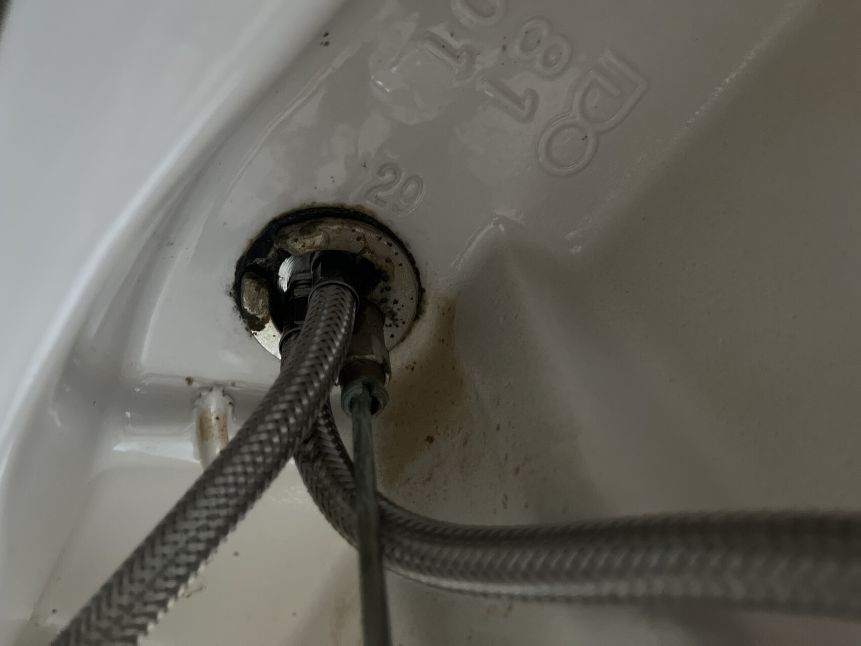 Unter dem Waschbecken sichtbare Rohre, Rostflecken und Feuchtigkeit am Abflussrohr.