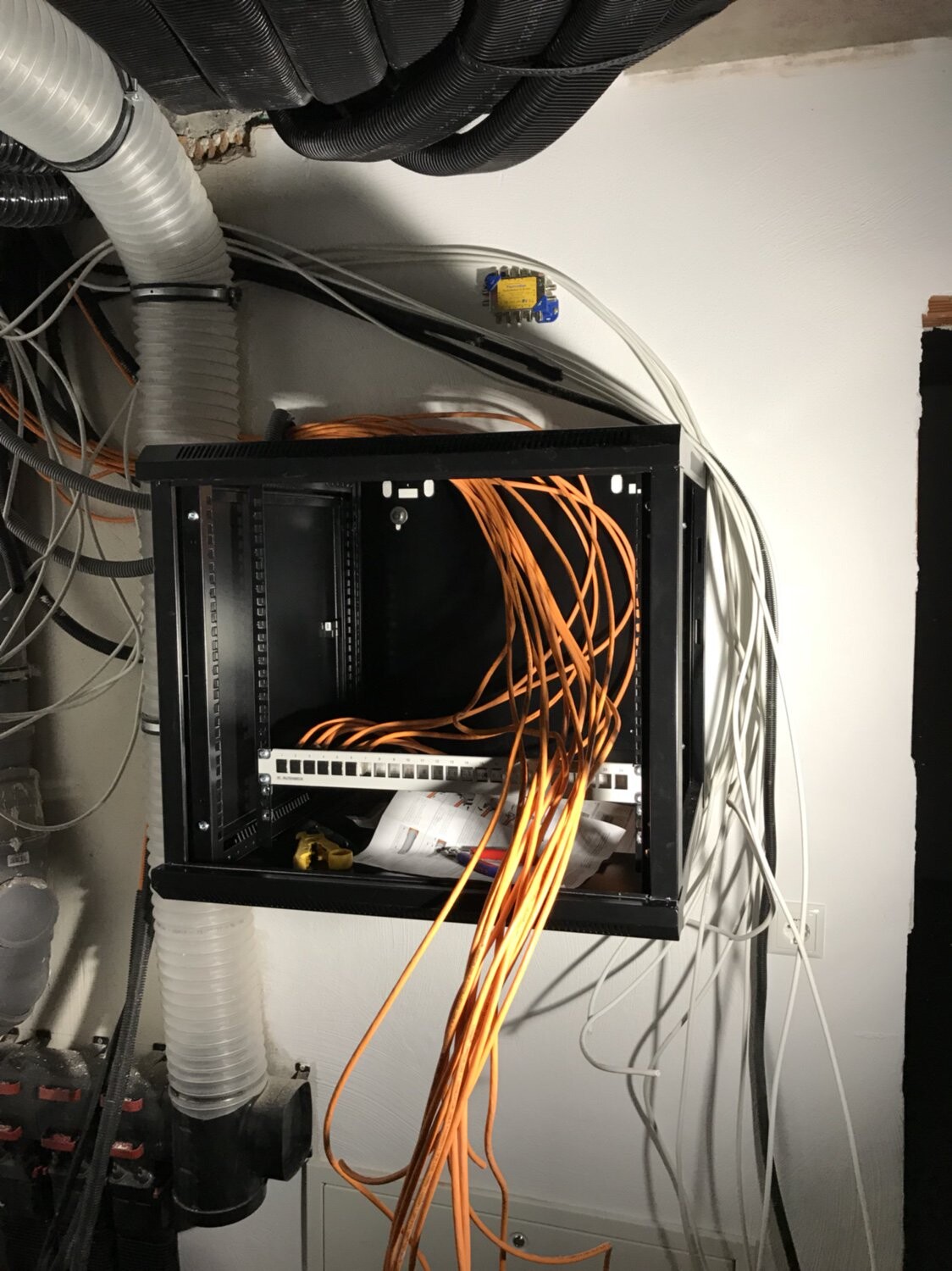 Netzwerk-Schrank mit Patchpanel, orange Kabelbündel, weiße Kabel und Kabelsalat.