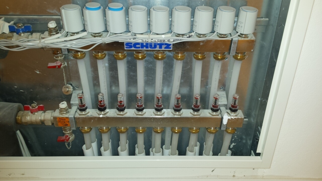 Hydraulik-Verteiler mit mehreren senkrechten Rohren, Ventilen und Messanzeigen in einer Metallbox.