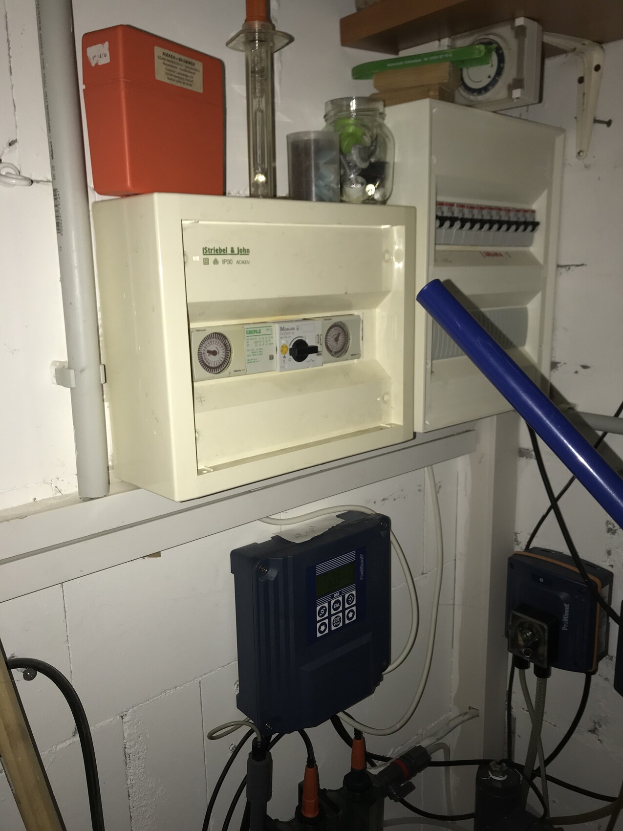 Kellerraum mit Verteilerschränken, Zähler, blauem Inverter und rotem Brandschutzkasten.