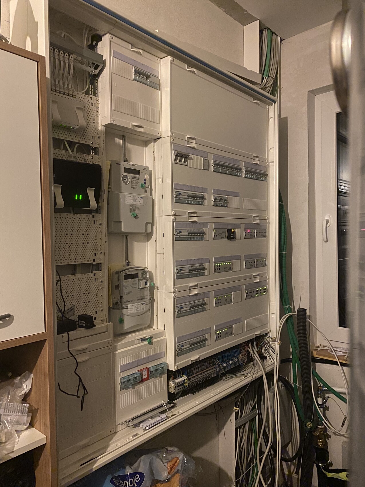 Schaltschrank mit DIN-rail-Modulen, mehreren Geräten und LEDs; zahlreiche Kabel sichtbar.