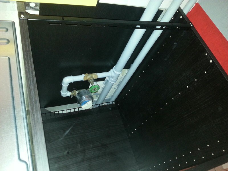 Wasserleitungen, Ventil und Wasserzähler hinter einem Installationsschrank