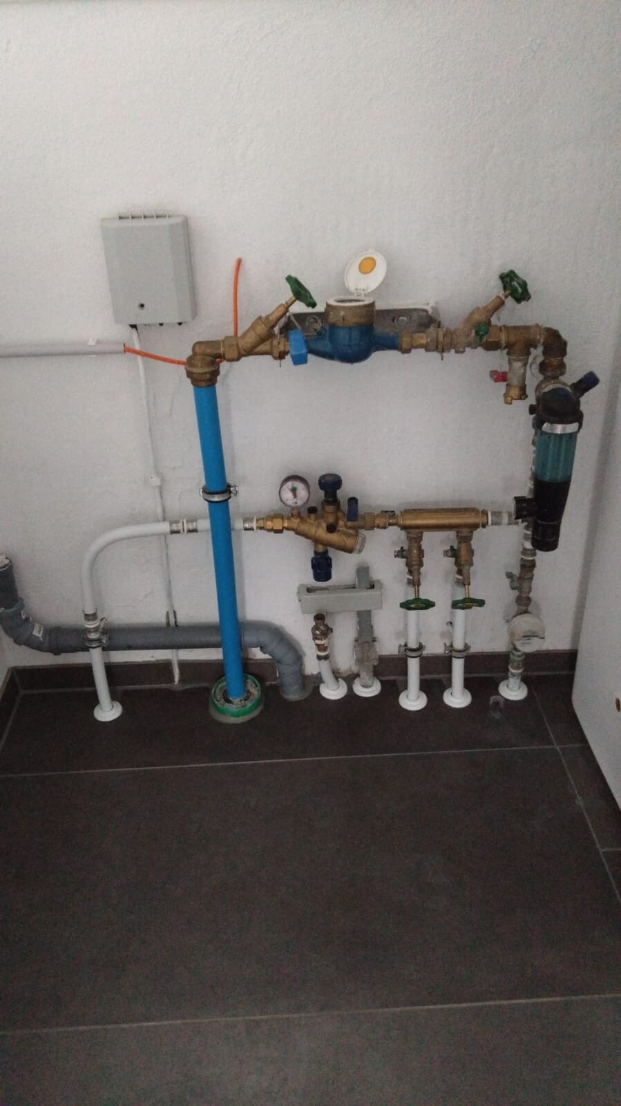 Wasserrohrleitungsanlage mit Ventilen, Manometer, Filter und Pumpe an der Wand.