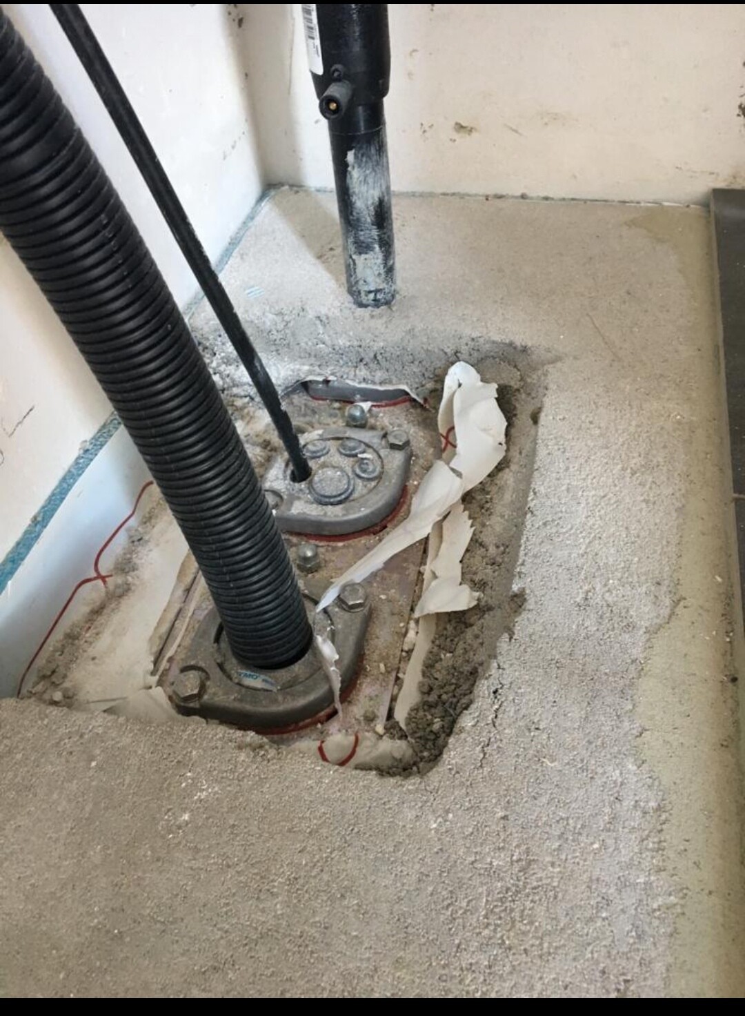 Baustelle: Bodenöffnung mit Wasserrohr, Schlauch und Zementreste im Bodenbereich