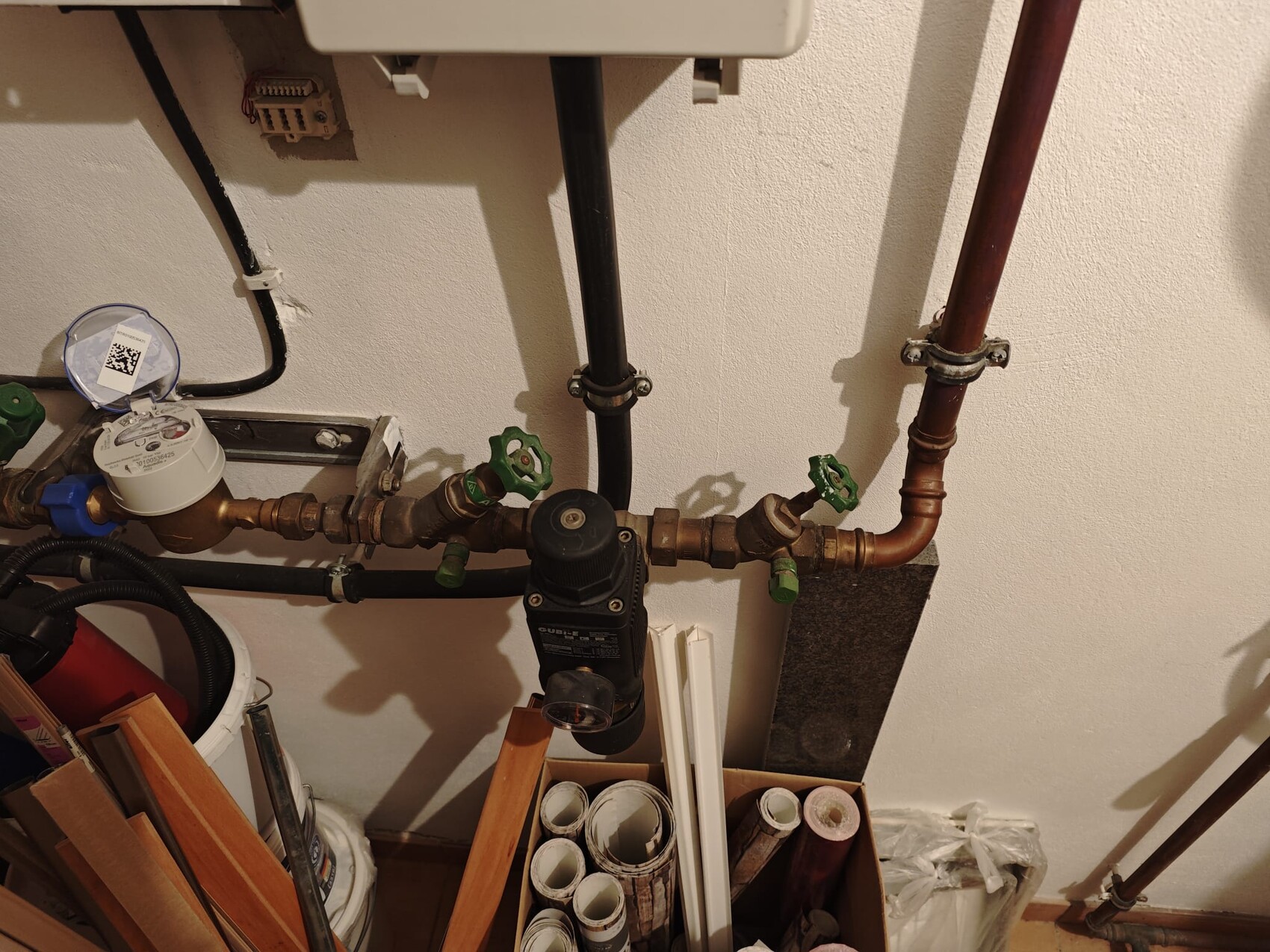 Haustechnikraum mit Wasserzaehler, Kupferrohren und gruene Ventile