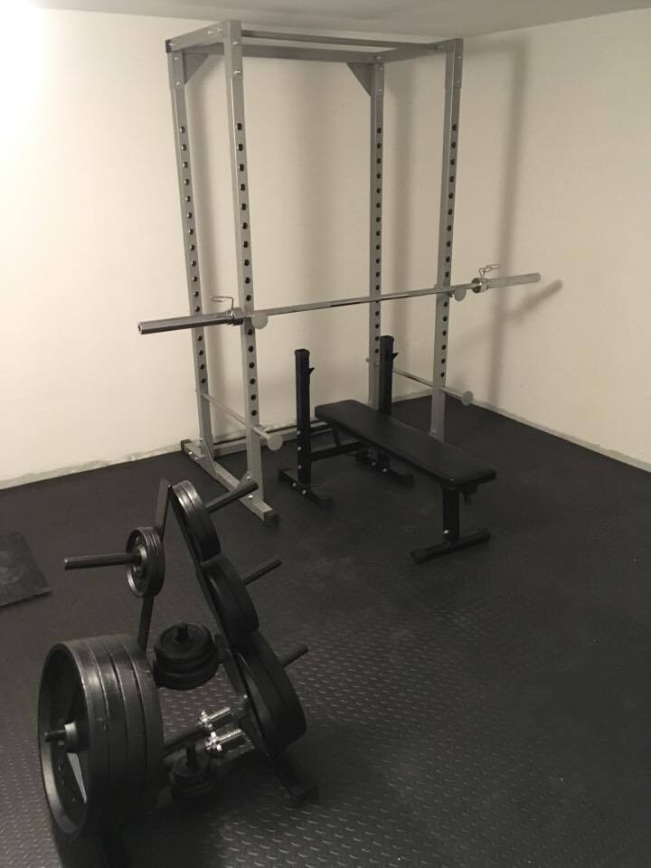 Heimfitnessraum mit Squat-/Power Rack, Langhantel, Flachbank und Gewichte.