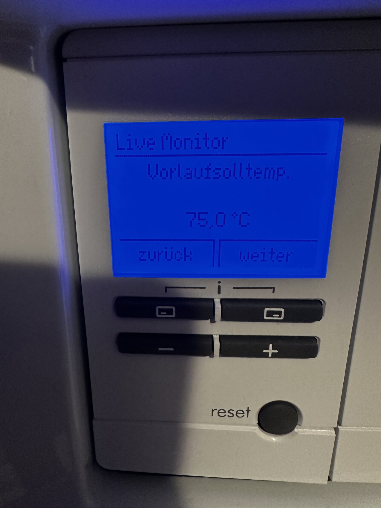 Blaues Display eines Geräts: Live Monitor, Vorlaufsolltemp. 75,0°C, Zurück/Weiter, Reset.