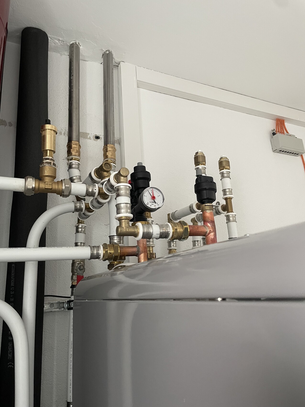 Heizungsanlage mit Kupfer- und Messingrohren, Ventilen und Druckmesser im Technikraum.