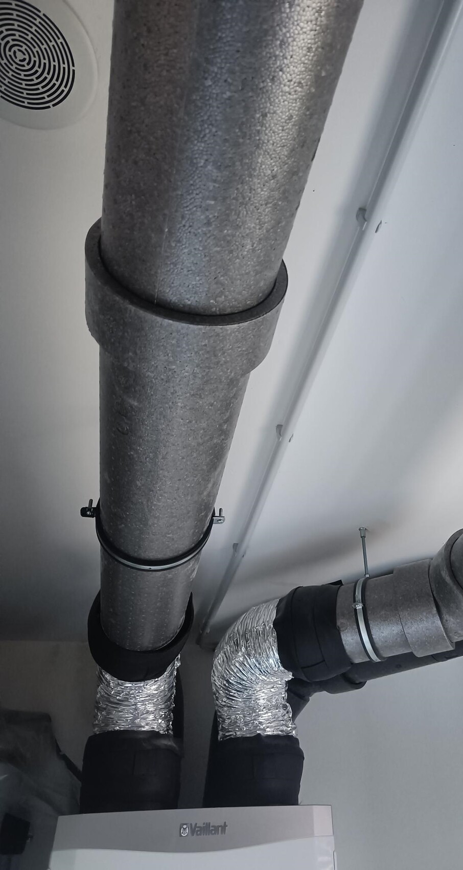 Heizungsrohre mit Dämmung und flexilem Rohrsystem im Technikraum, Vaillant Boiler sichtbar