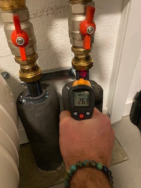 Nahaufnahme von zwei Kupferrohren mit roten Absperrventilen; Messgerät zeigt 26,3 °C an.