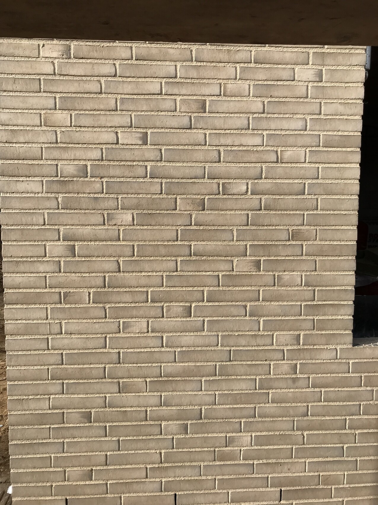 Hellbeige Ziegelwand Außenfassade mit dunkler Öffnung.