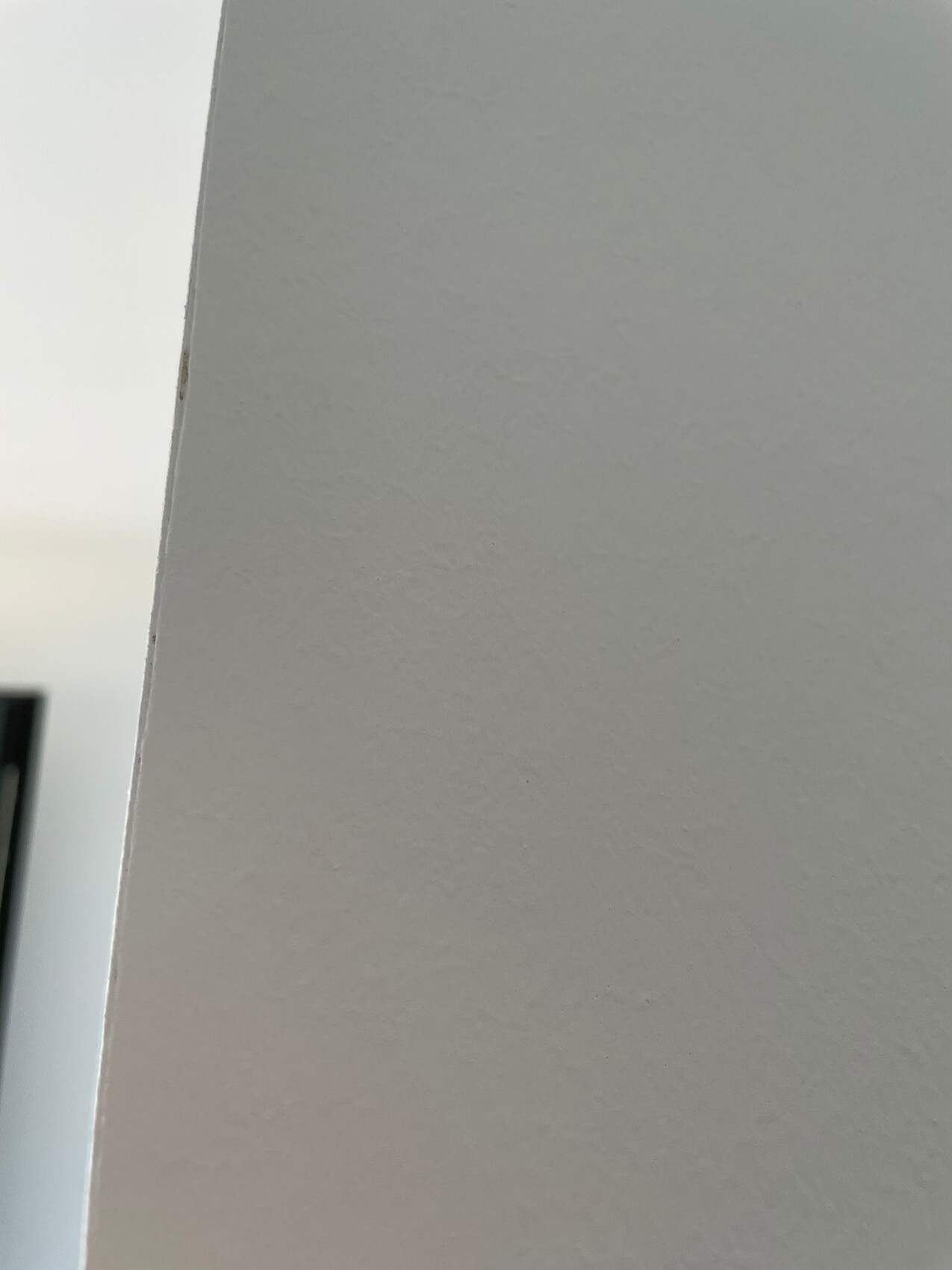 Nahaufnahme einer hellgrauen, leicht texturierten Wandfläche; linke Kante sichtbar.