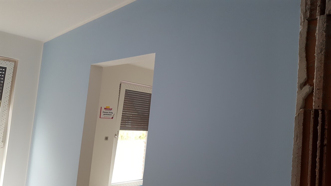 Blaue Innenwand in renoviertem Raum mit Fenster und offener Wandseite rechts