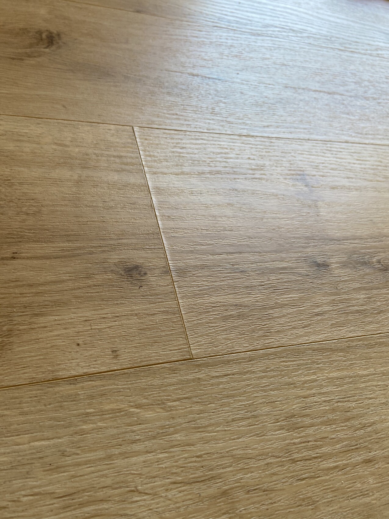 Nahaufnahme eines Holzfußbodens mit sichtbarer Maserung und Fugenlinien.