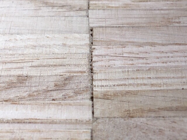 Nahaufnahme von Holzplatten mit sichtbarer Fuge und rauer Maserung.