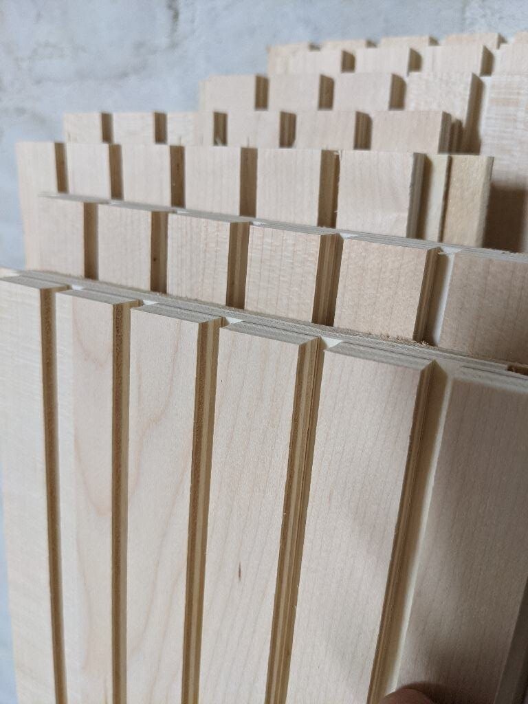 Mehrere parallele Holzlatten mit vertikalen Rillen, Nahaufnahme von Holzstücken.
