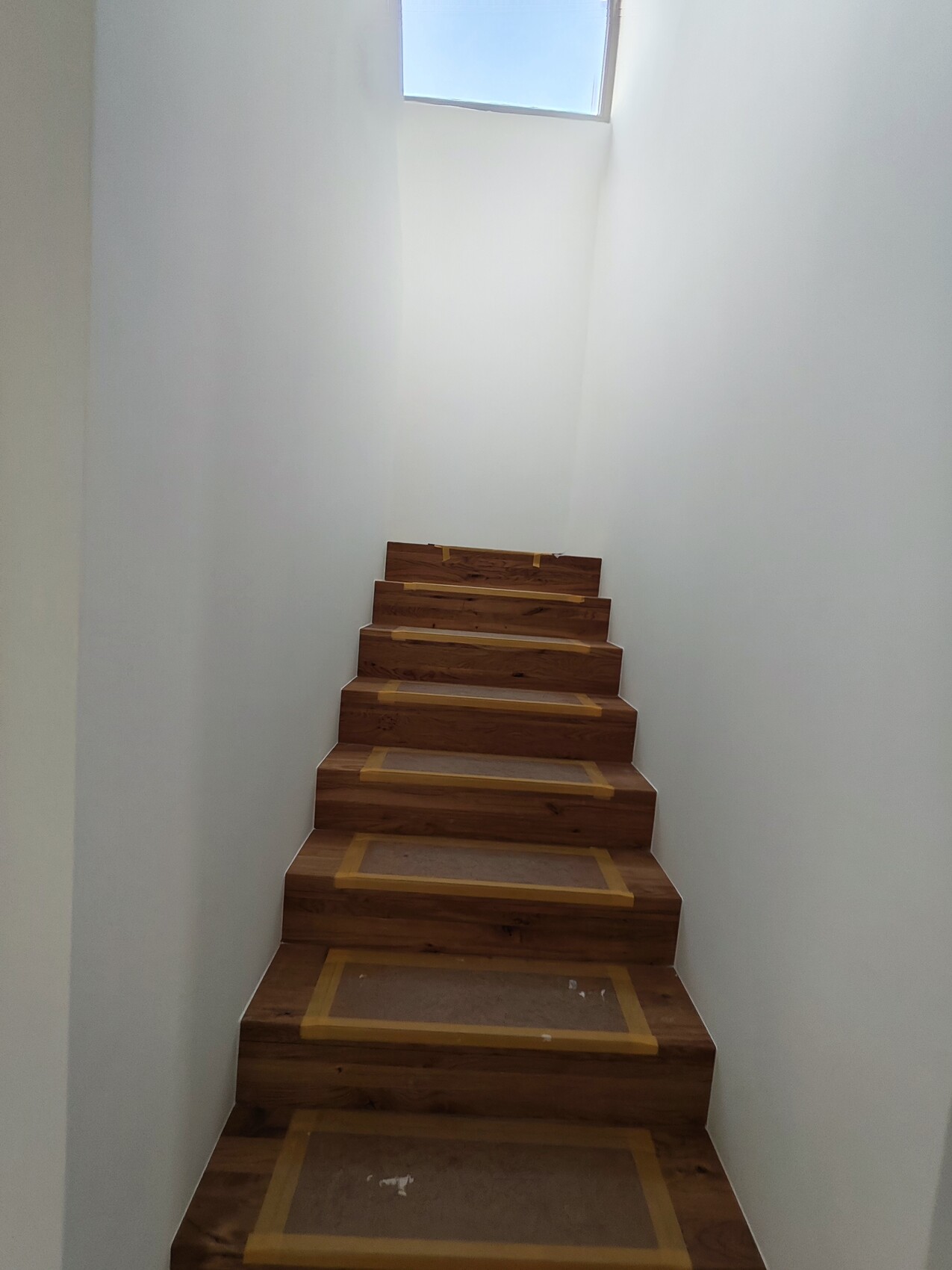 Helle Holztreppe in engem Flur mit Oberlicht-Dachfenster