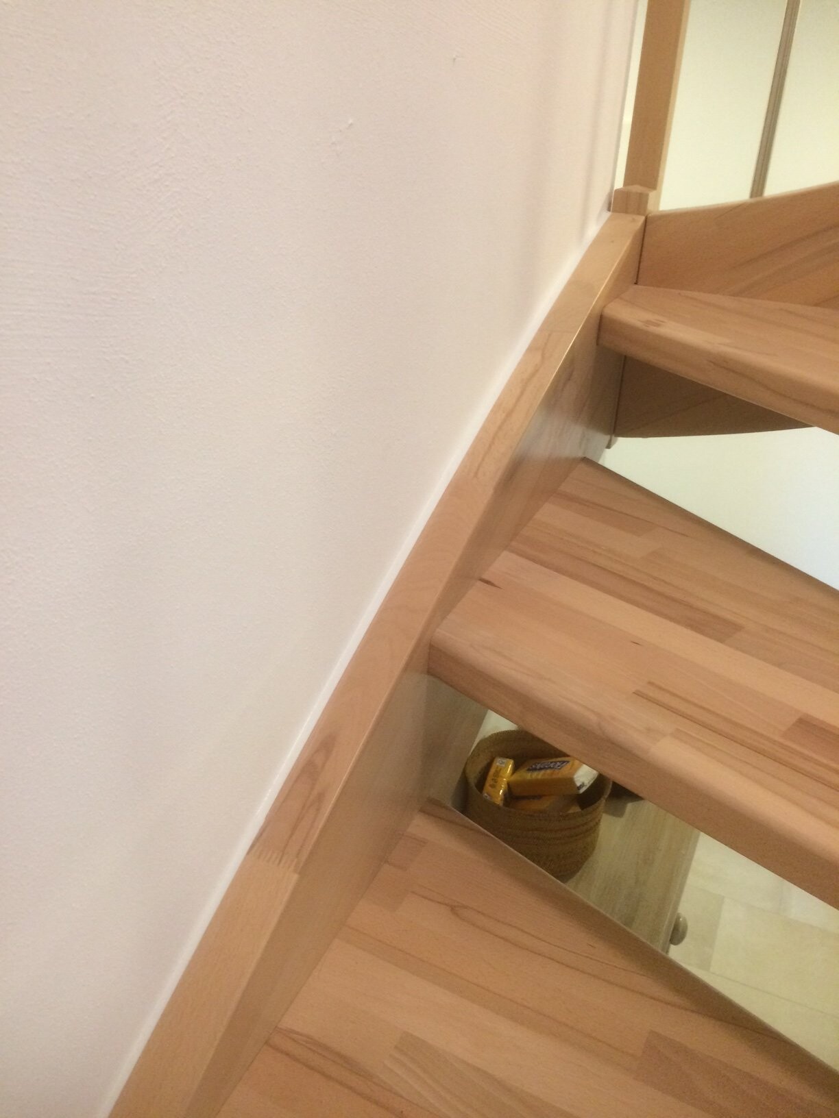 Helle Holztreppe mit offenen Stufen; unterhalb eines Korbs mit Snackriegeln.