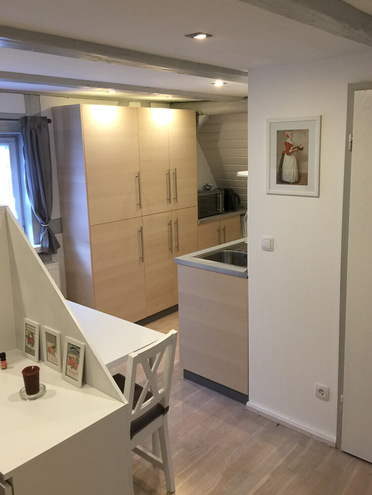 Helle Küche mit Holzschränken, Spüle auf Halbinsel, Esstisch und Wandbild.