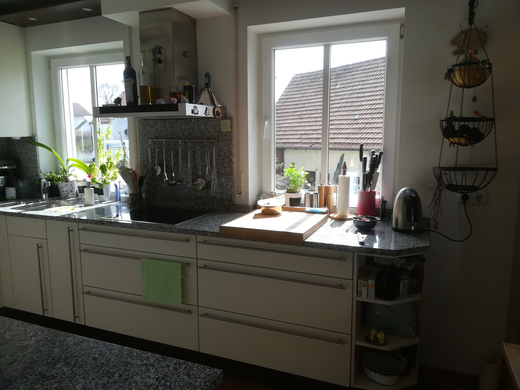 Küche mit Granit-Arbeitsplatte, Spüle links, Fenster nach außen, Utensilienhaken.