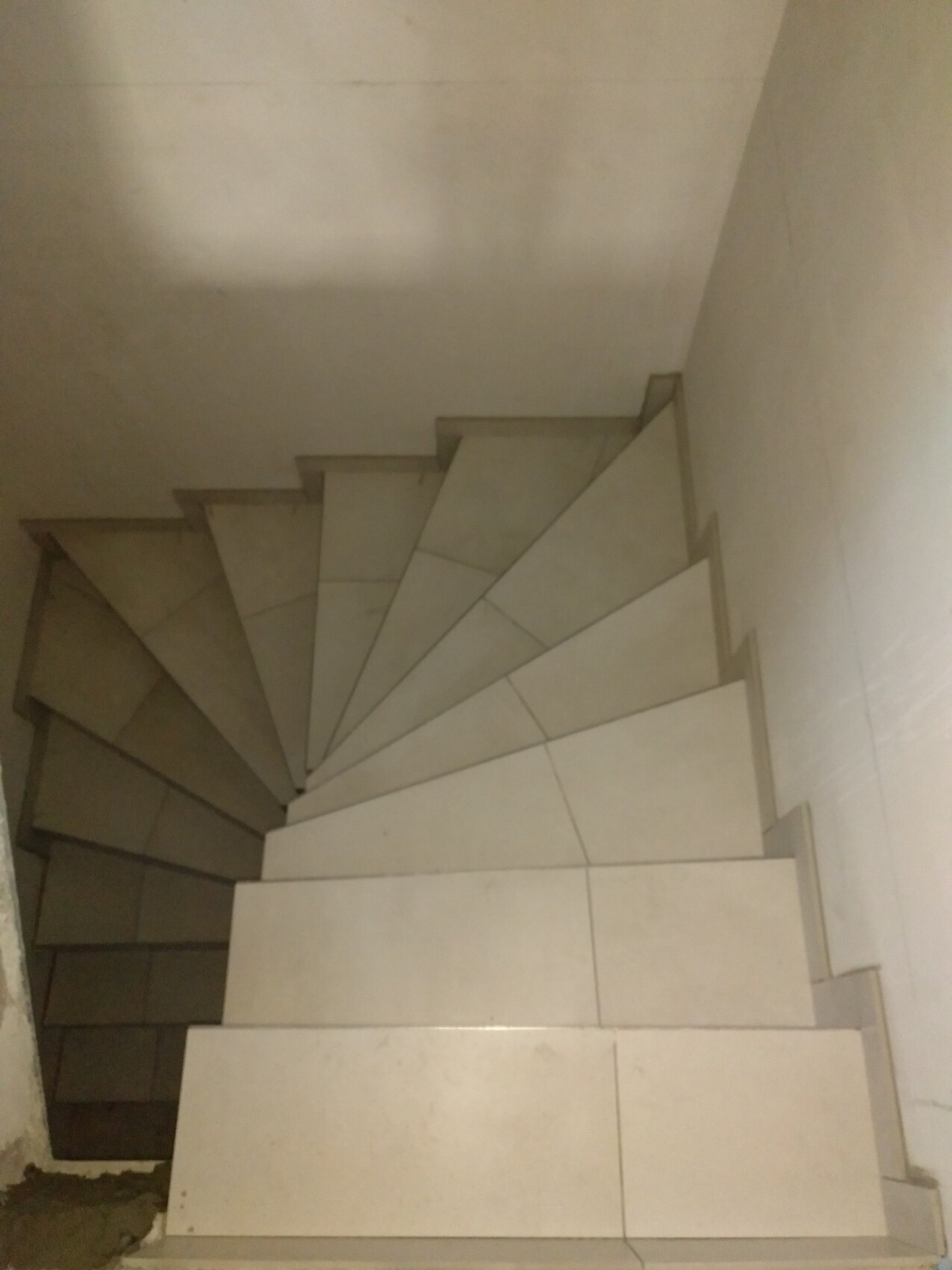 Spiraltreppe aus hellen Stufen im Innenraum, Blick von oben auf die Wendung.