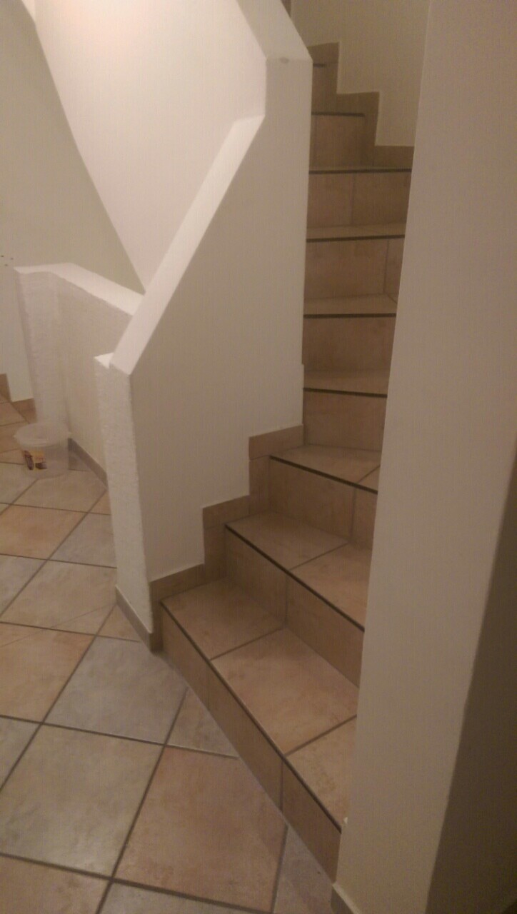 Innenansicht einer beige gefliesten Treppe mit weißen Wänden