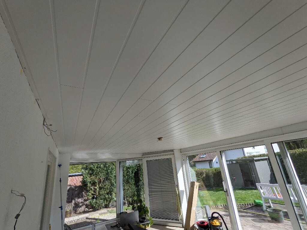 Veranda mit weißer Paneeldecke und Glasfronten; Blick in den Garten, Werkzeuge im Raum