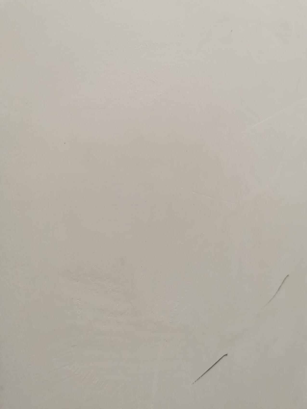 Helle cremefarbene Wand mit leichten Kratzern und Unebenheiten.