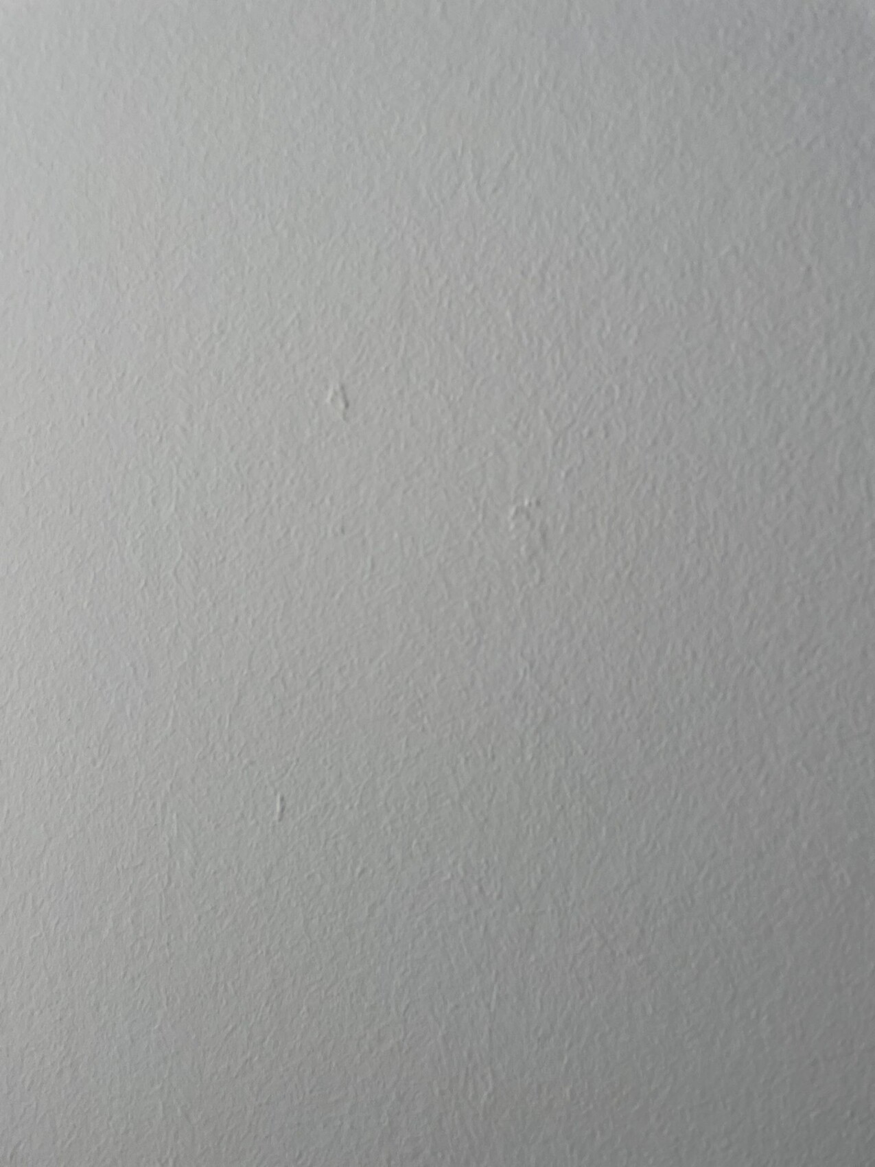 Weiße Wand mit feiner Textur; keine Gegenstände sichtbar.