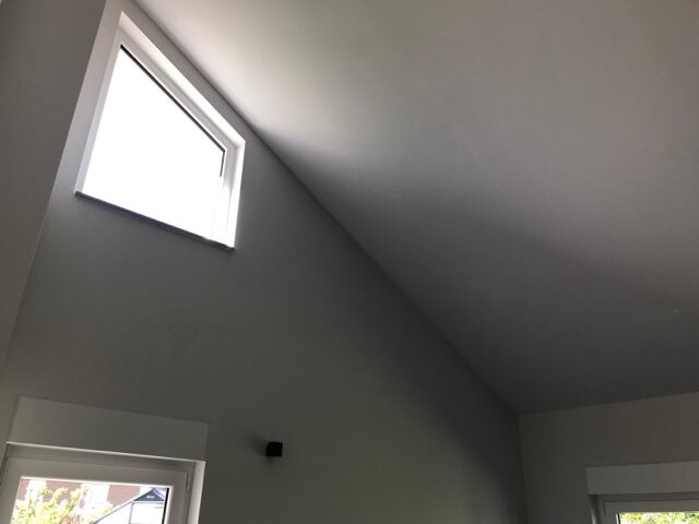 Heller Innenraum mit schräger Decke; links oben ein Oberlichtfenster, unten links ein weiteres Fenster.