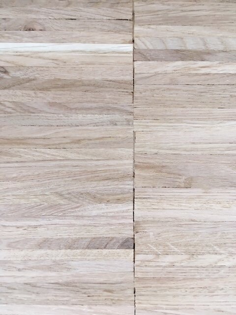 Heller Holzboden mit langen Dielen und zentraler Fuge in der Bildmitte.