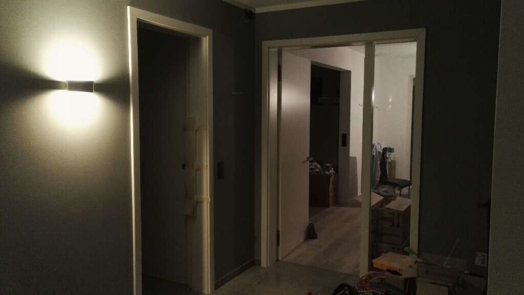 Heller Flur mit offenen Türen und Lampenlicht im Innenraum eines Hauses.